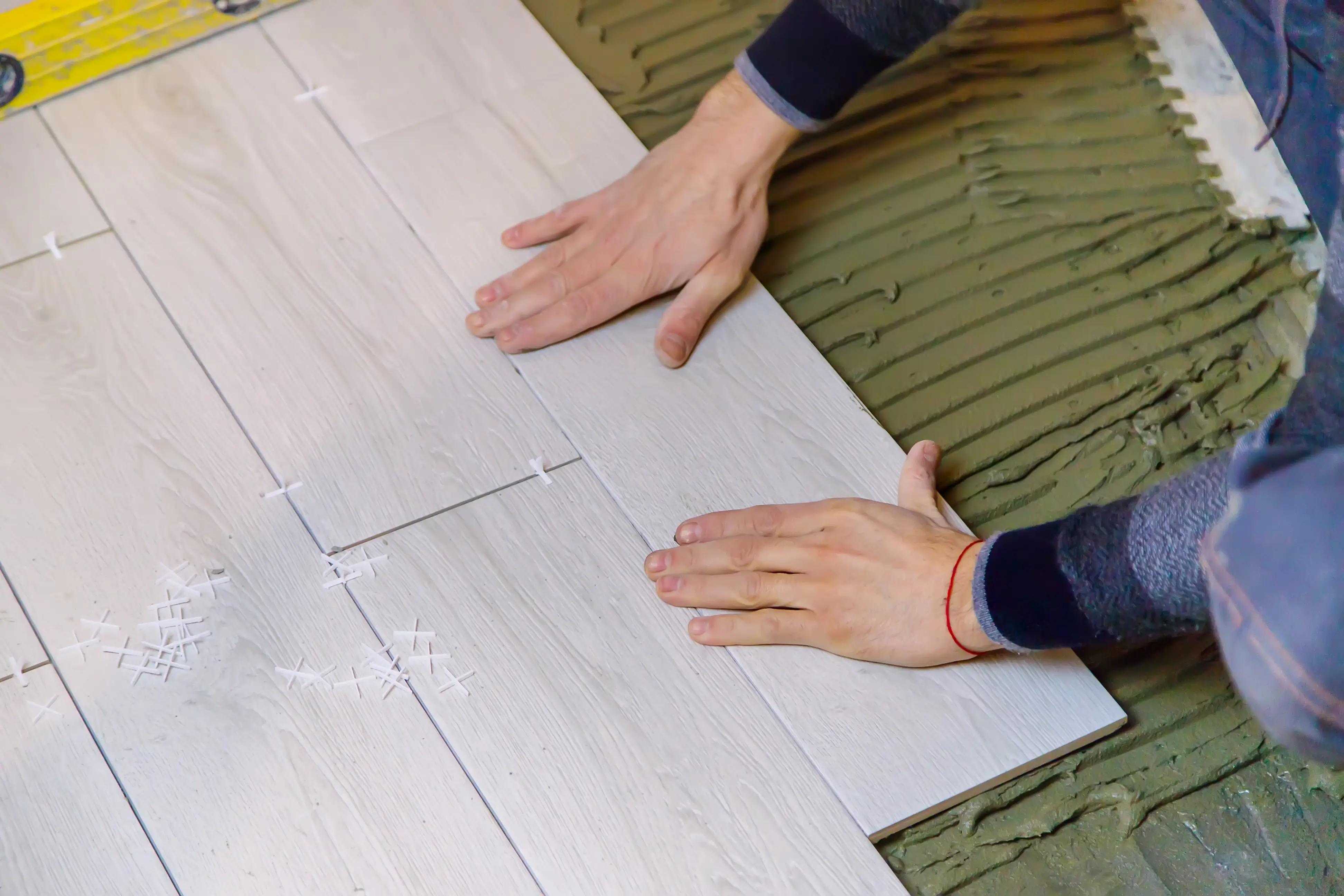 Contractor aligning ceramic tiles on adhesive during flooring installation, showcasing precise placement and professional craftsmanship.